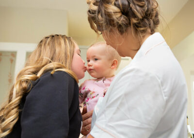 a bridesmaid kisses the cheek of the bride's baby daughter by Anglesey wedding photographer, North Wales, Gill Jones Photography