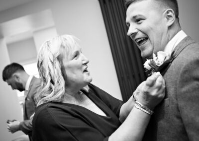 the groom's mother fastens a button hole to her son by Anglesey wedding photographer, North Wales, Gill Jones Photography