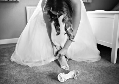 the bride bends over to fasten her shoe by Anglesey wedding photographer, North Wales, Gill Jones Photography