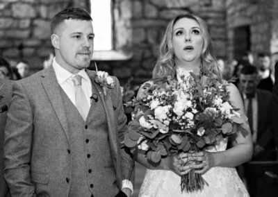 bride and groom stand next to each other at the alter, the bride breathes out a sigh of relief by Anglesey wedding photographer, North Wales, Gill Jones Photography