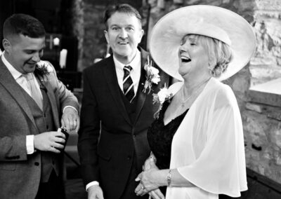 bride's mother laughs as the groom closes the lid of a hip flask by Anglesey wedding photographer, North Wales, Gill Jones Photography