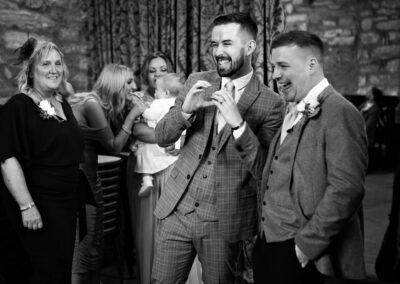 guest creates a heart with his hands and looks towards the bride by Anglesey wedding photographer, North Wales, Gill Jones Photography