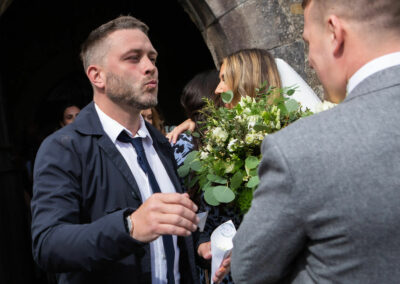 guest puckers his lips as if to kiss the groom by Anglesey wedding photographer, North Wales, Gill Jones Photography
