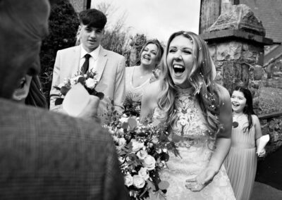 bride leans towards an onlooker and laughs out loud by Anglesey wedding photographer, North Wales, Gill Jones Photography