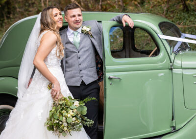 bride and groom stand casually by their wedding car by Anglesey wedding photographer, North Wales, Gill Jones Photography