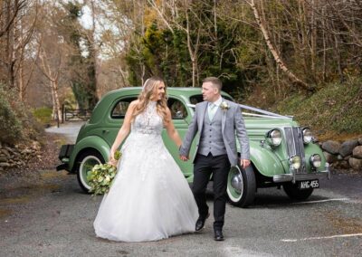 bride and groom walk hand in hand chatting with a fabulous green car in the backgroundby Anglesey wedding photographer, North Wales, Gill Jones Photography