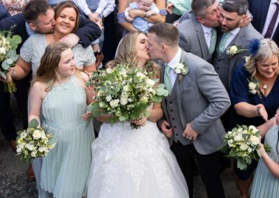 group of wedding guests kiss the person standing next to them by Anglesey wedding photographer, North Wales, Gill Jones Photography