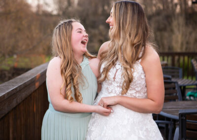 bride holds hand and laughs with young brides maid by Anglesey wedding photographer, North Wales, Gill Jones Photography