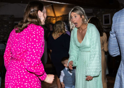 woman looks at friend in shock on dance floor by Anglesey wedding photographer, North Wales, Gill Jones Photography