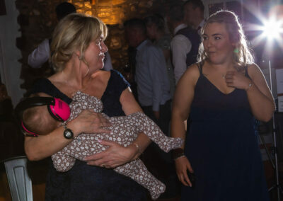 grandmother holds baby granddaughter who's wearing ear defenders by Anglesey wedding photographer, North Wales, Gill Jones Photography