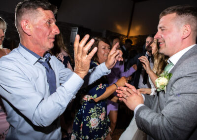 two gentlemen hands held high dancing by Anglesey wedding photographer, North Wales, Gill Jones PhotographyGill Jones Photographer