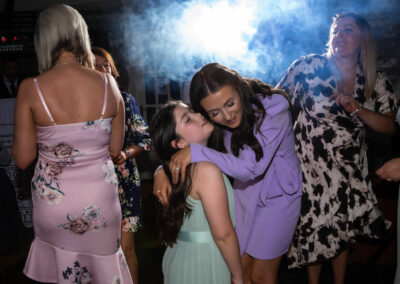 young bridesmaid whispering to young lady on the dance floor by Anglesey wedding photographer, North Wales, Gill Jones Photography Gill Jones Photographer