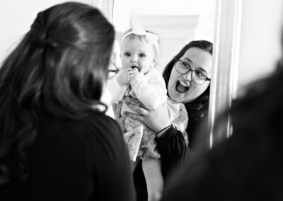 auntie holding her niece up to a mirror and laughing