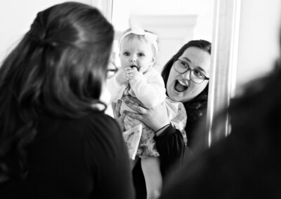 auntie holding her niece up to a mirror and laughing