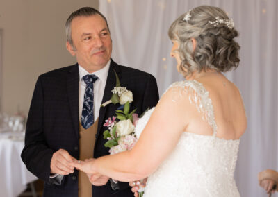 bride offers her hand to the groom to accept her ring