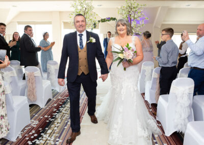 bride and groom walk out of the ceremony room, hand in hand