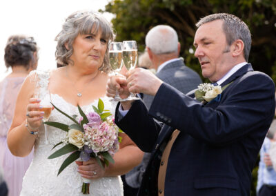 groom compares contents level of his champagne to his brides' glass