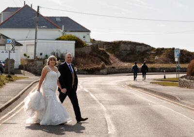 bride and groom crossing the road with two people walking away in the background