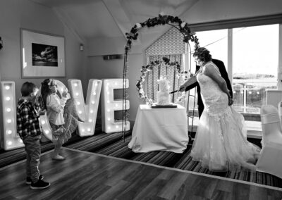 bride and groom cut the cake whilst the children try to take the photograph also