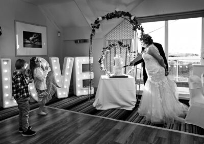 bride and groom cut the cake whilst the children try to take the photograph also