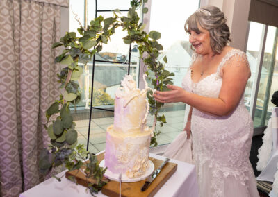bride leans towards her wedding cake to point at the detail
