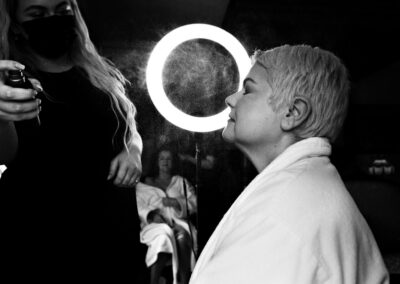 setting spray being sprayed at a bridesmaid's face, a light shining behind her by Anglesey wedding photographer Gill Jones Photography