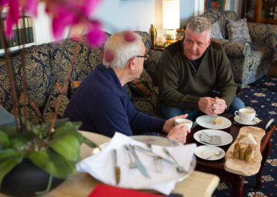 groom and bride's father chatting over lunch in Plas Dinas reception room by Anglesey wedding photographer Gill Jones Photography