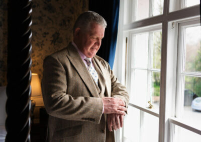 groom checking his watch by a window at Plas Dinas by Anglesey wedding photographer Gill Jones Photography