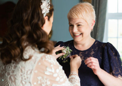 bride fixing a flower to her bridesmaid by Anglesey wedding photographer Gill Jones Photography