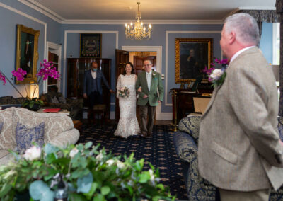 bride walking towards groom in the reception room at Plas Dinas by Anglesey wedding photographer Gill Jones Photography