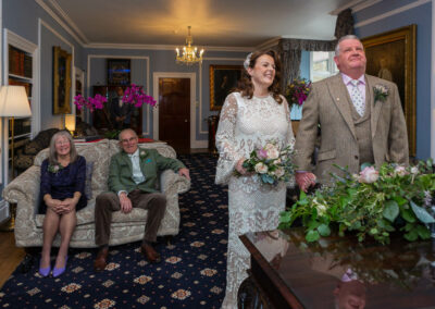 bride and groom holding hands looking towards the registrar by Anglesey wedding photographer Gill Jones Photography