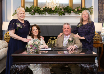 bride and groom at their witnesses standing behind a desk by Anglesey wedding photographer Gill Jones Photography