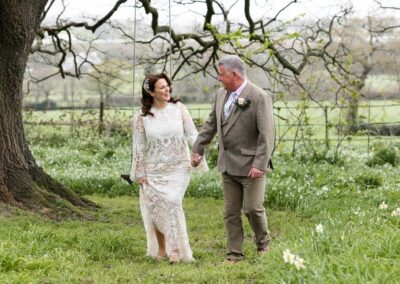 bride and groom chatting and walking hand in hand by Anglesey wedding photographer Gill Jones Photography