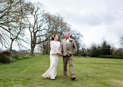 bride and groom hand in hand walking back towards Plas Dinas by Anglesey wedding photographer Gill Jones Photography