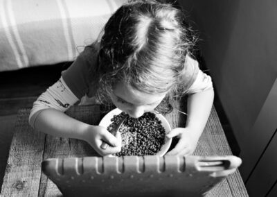 a little girl spoons some coco pops into her mouth whilst watching a screen by Anglesey photographer Gill Jones Photography