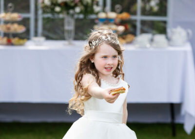a bridesmaid holds a cake and walks forward by Anglesey photographer Gill Jones Photography