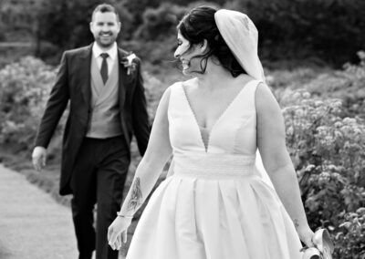 a bride turns her face to look at her groom as they walk along a country path by Anglesey photographer Gill Jones Photography