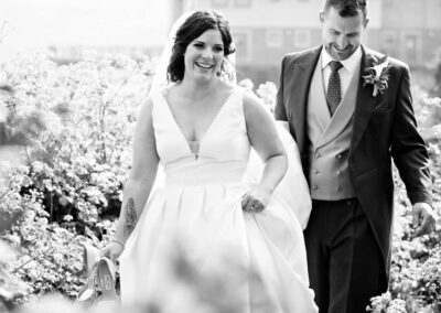 the bride and groom are surrounded by wild flowers as they walk along a path by Anglesey photographer Gill Jones Photography