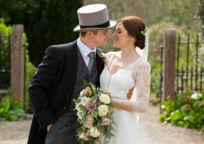 groom wearing top hat leans towards his bride to kiss her