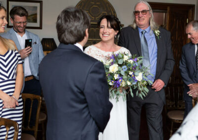 bride has entered ceremony room and walks towards her groom smiling by Anglesey wedding photographer Gill Jones Photography
