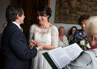 bride smiles the biggest smile as a ring is put on her finger by the groom by Anglesey wedding photographer Gill Jones Photography wedding photographer Gill Jones Photography