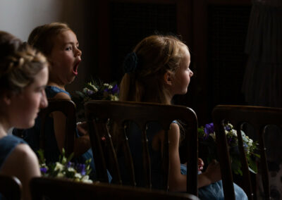 little bridesmaid yawns widely during the wedding ceremony by Anglesey wedding photographer Gill Jones Photography