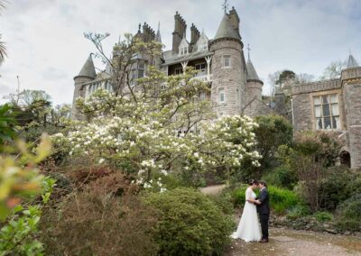 bride and groom standing with their foreheads touching slightly, in front of a gothic type building by Anglesey wedding photographer Gill Jones Photography