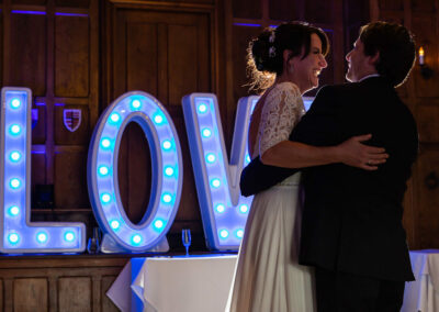 the bride and groom having their first dance with the word love behind them by Anglesey wedding photographer Gill Jones Photography