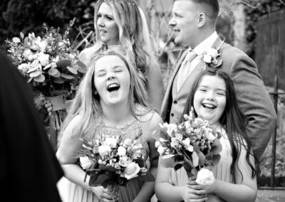 two bridesmaids holding bouquets laughing alot by Anglesey photographer Gill Jones