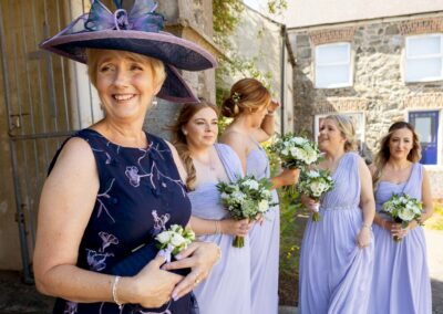 the bride's mother is waiting patiently for her daughter to arrive, the bridesmaids are behind her chatting by Anglesey photographer Gill Jones
