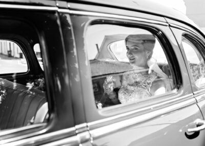 bride sitting in the back of the wedding car holding a champagne glass by Anglesey photographer Gill Jones