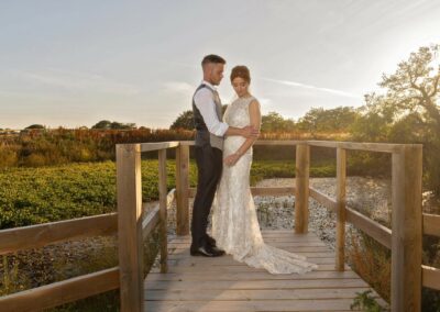 groom holding his bride whilst standing on the jetty at Henblas Country Park by Anglesey photographer Gill Jones