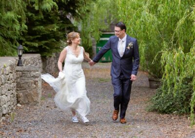 couple hand in hand running whilst looking at one another by Anglesey wedding photographer Gill Jones