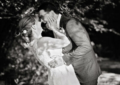 couple facing eachother she has her partner's face in her hands and they're laughing by Anglesey wedding photographer Gill Jones